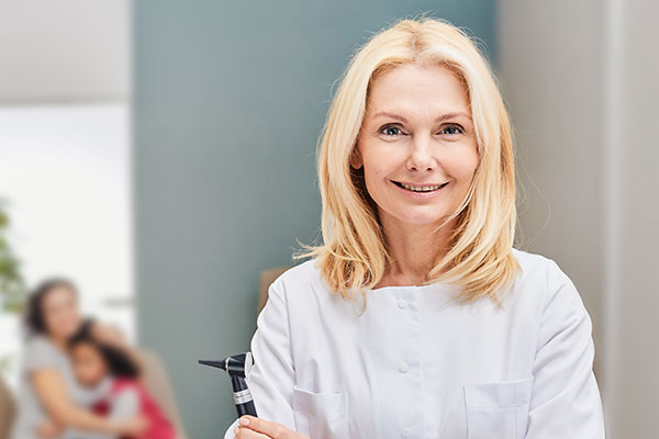 Smiling audiologist holding an otoscope.